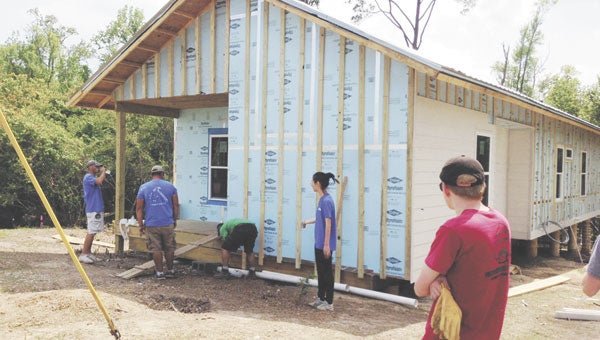 Habitat volunteers work to install insulating foam board underneath the exterior siding of the house.
