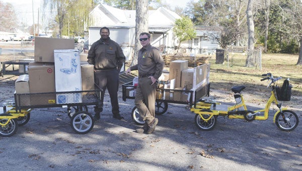 Shown with the trike bikes are Michael Delaney, on-car supervisor for the Evergreen center of UPS, and Samaj Nared, who was been a “Christmas helper” for UPS.|Photo by Allison Brown