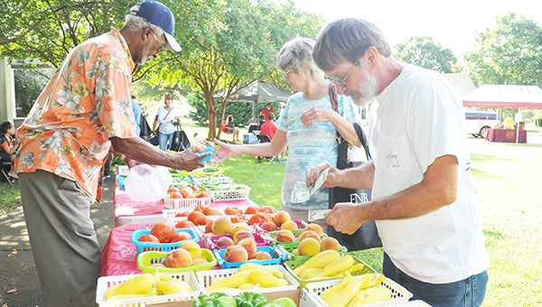 Calvin and Debbie Hyer of Walnut Hill, Fla., buy produce from Edward Adams at Market in the Park Saturday at Heritage Park. | Andrew Garner/Atmore Advance